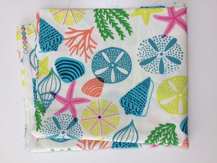 fabric with white background and teal, yellow, pink and green shells