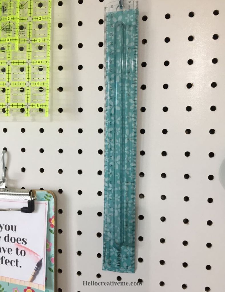 clear ruler with blue paper behind it on pegboard