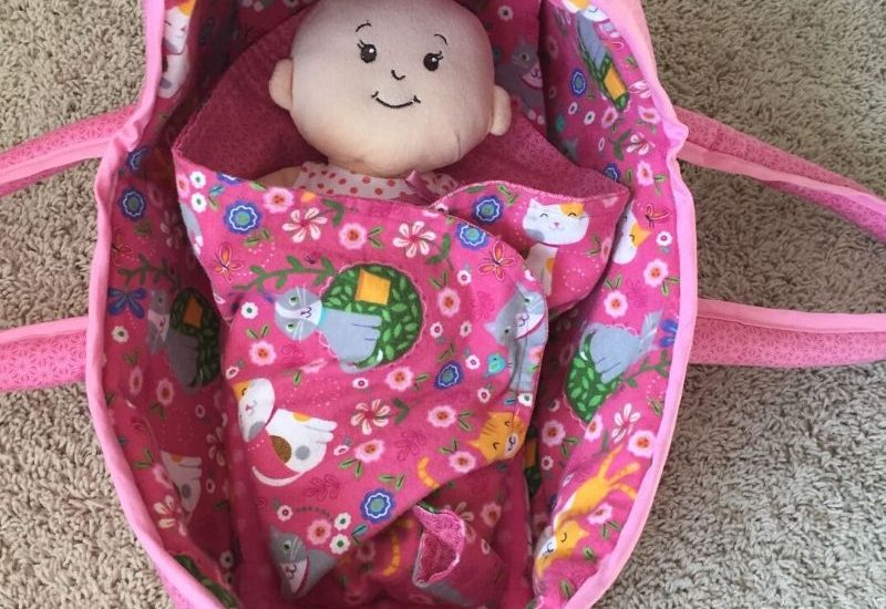baby doll in pink handmade fabric doll basket.