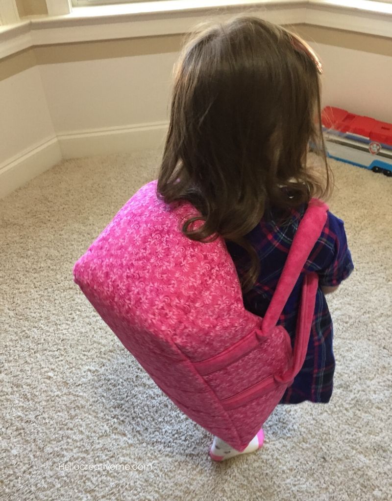 girl wearing doll basket as backpack