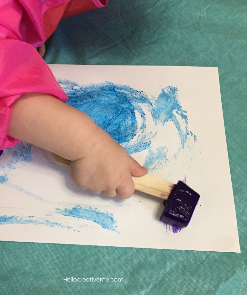 girl painting with frozen purple ice cube on paper