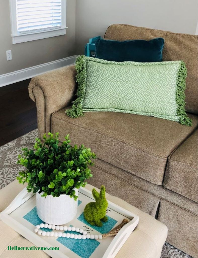green lumbar pillow in front of teal pillow on couch