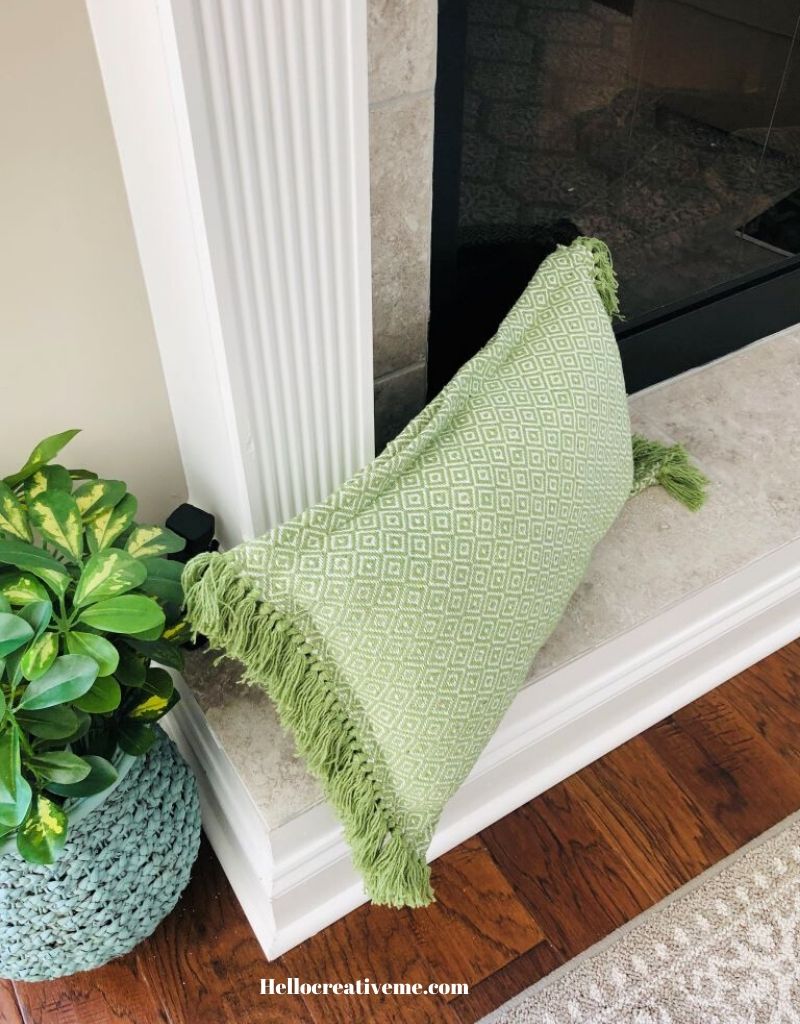 green DIY pillow next to fireplace