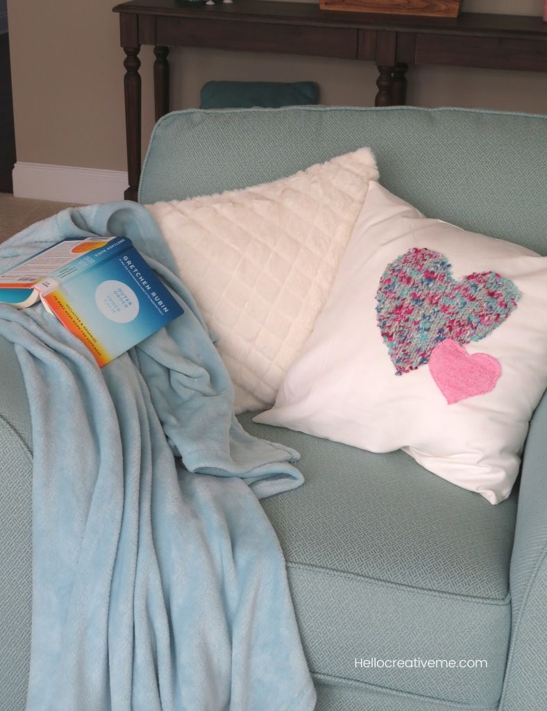 White heart pillows in blue chair with a book