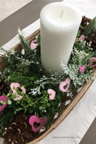 white candle with greenery and pink hearts