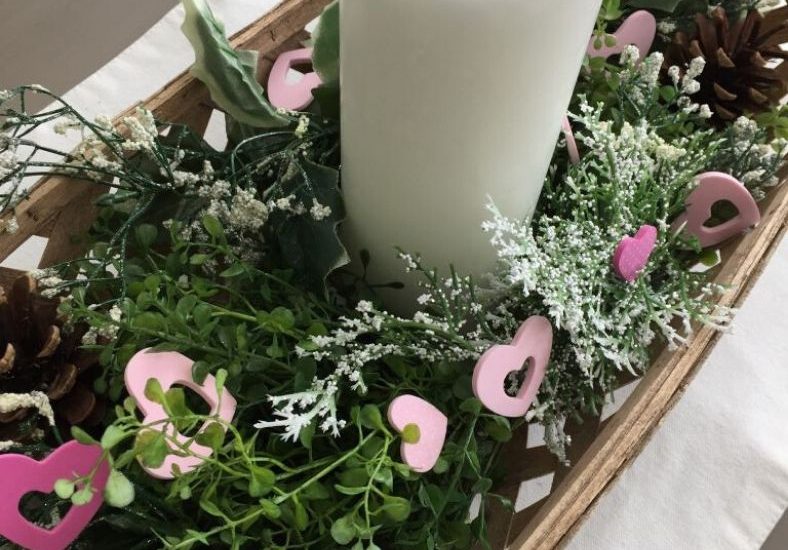 white candle with greenery and pink hearts