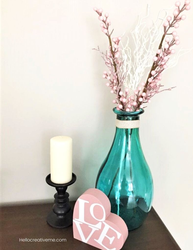 blue vase with pink stems , candle, and wooden heart