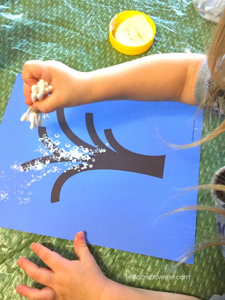Child painting winter tree with white paint