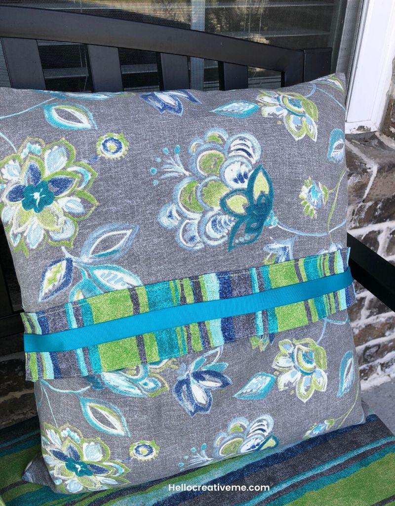 Gray floral pillow with striped fabric and teal ribbon trim for no cost spring porch refresh.