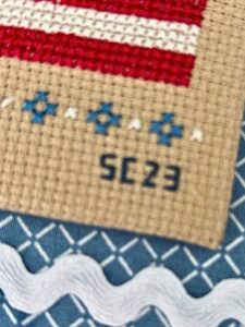 Close up of corner of cross stitched piece with initials and date of completion.
