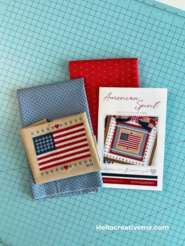 Stitched American flag cross stitch shown with pattern and coordinating red and blue quilting fabrics.